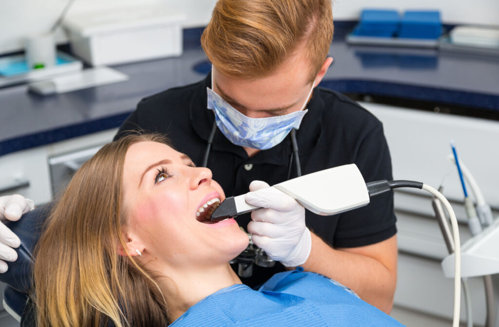 A male dentist is scanning the teeth of a female patient with CEREC scanner in a dental clinic.