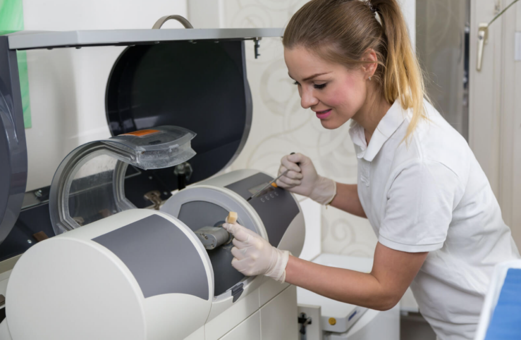 Dentist's assisstant operating CEREC Milling machine to produce dental implants