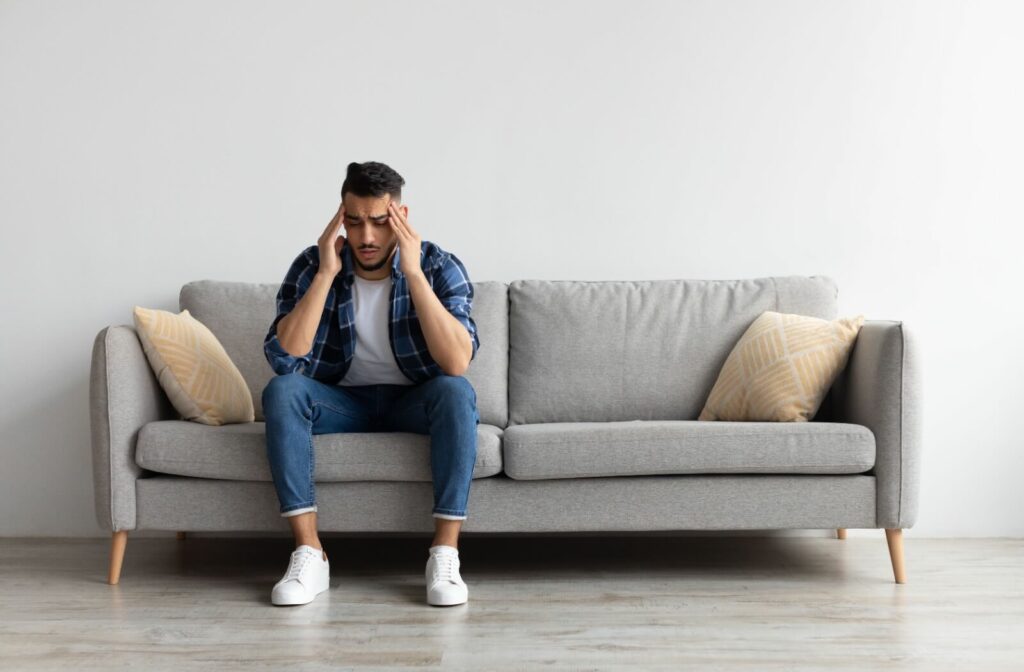 A man in a blue flannel suffering from a headache possibly caused by cavities.