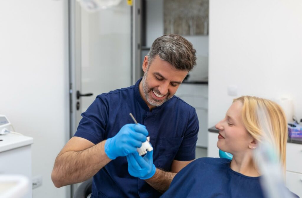 A dentist showing a patient a model of human teeth while explaining about dental crowns and how long they last.